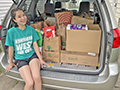  Student Caroline Rapp posing with donated food items as part of her IB CAS Project